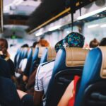 Wnętrze autokaru wypełnione pasażerami siedzącymi w niebiesko-beżowych fotelach.